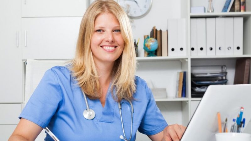 Confident,Blond,Woman,Doctor,Sitting,At,Workplace,With,Computer,In
