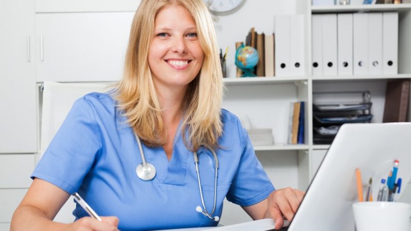 Confident,Blond,Woman,Doctor,Sitting,At,Workplace,With,Computer,In