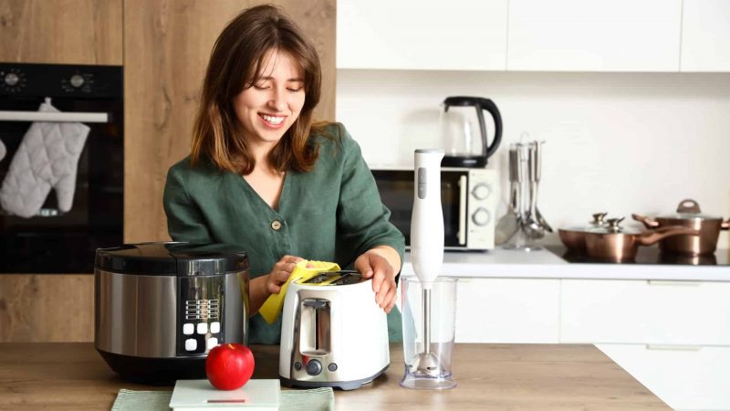 Young,Woman,Cleaning,Electric,Toaster,In,Light,Kitchen